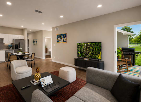 A modern living room with a grey couch, a black coffee table, and a red rug.