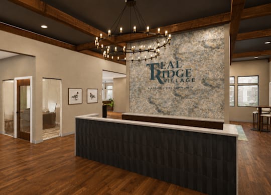 A reception area for Real Ridge Village Community with a stone backdrop and a black reception desk.