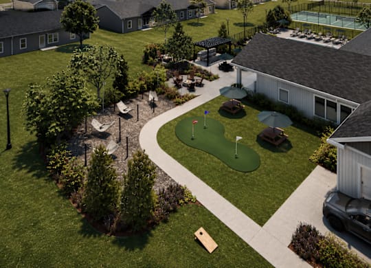 A golf course is surrounded by a green lawn and a few buildings.