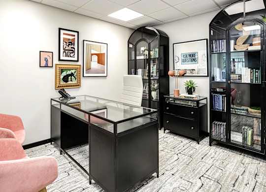 A black and white office with a glass desk and a pink chair.