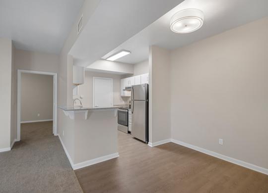 A kitchen area with a refrigerator, sink, and cabinets.