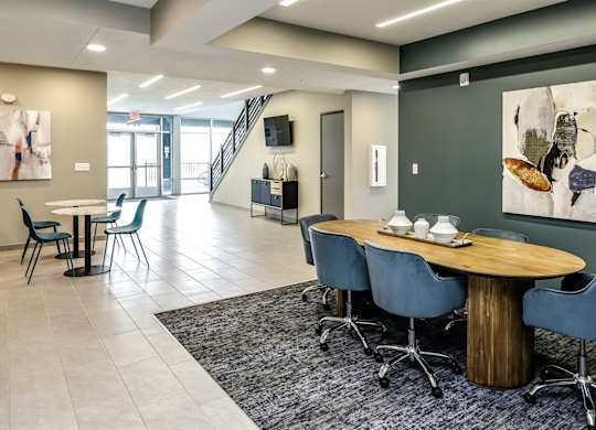 A modern dining room with a round wooden table and blue chairs.