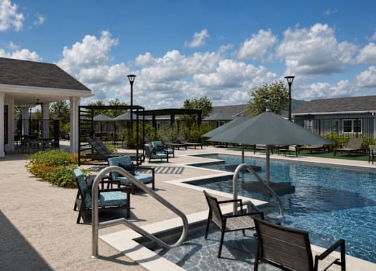A poolside area with chairs and an umbrella.