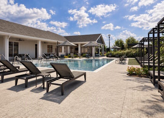 A poolside area with lounge chairs and a house in the background.