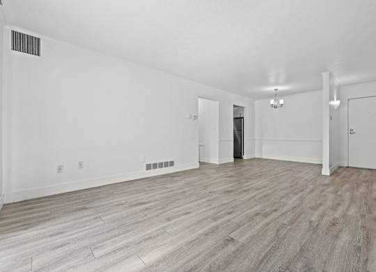 A spacious room with wood flooring and white walls.