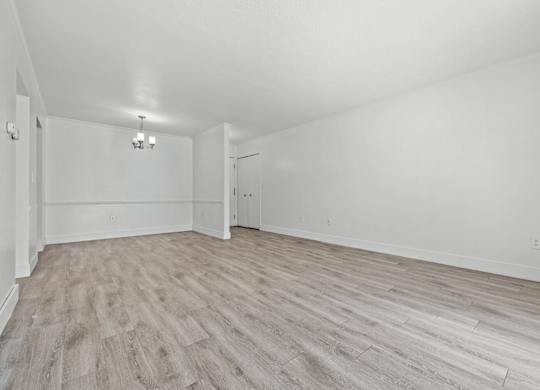 A room with light wood flooring and white walls.