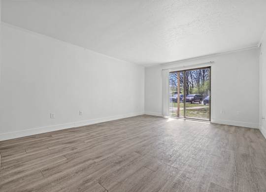 A room with wooden flooring and a window showing an outdoor scene.