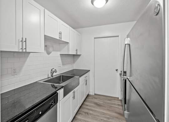 A kitchen with white cabinets and a black counter top.