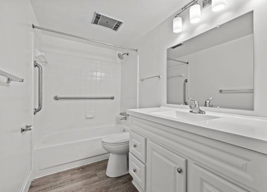 A white bathroom with a toilet, sink, and shower.
