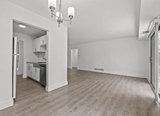 A spacious kitchen with white cabinets and a refrigerator is visible.