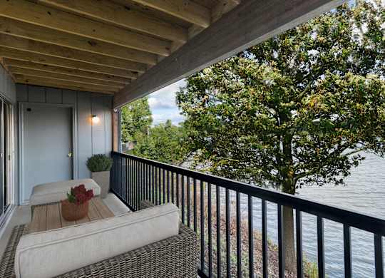 A balcony with a couch and a view of the water at The Waverly on the Lake - Belleville, MI Apartment, Belleville, MI, 48111