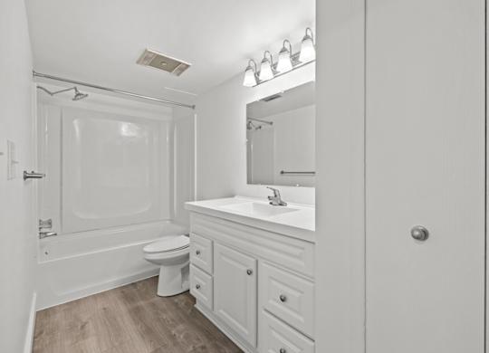 A white bathroom with a toilet, sink, and mirror.