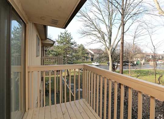 a balcony with a wooden railing and a street in the background