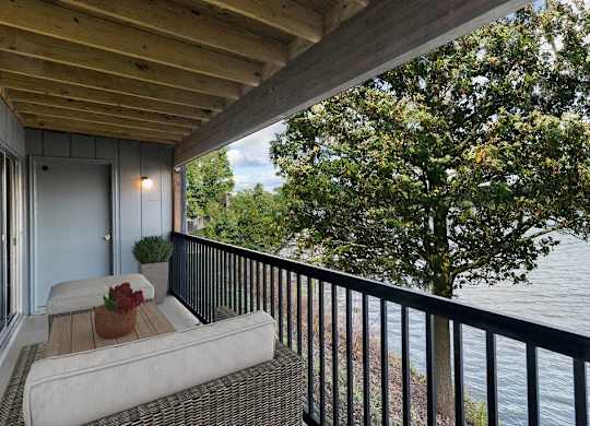 A balcony with a couch and a view of the water at The Waverly on the Lake - Belleville, MI Apartment , Belleville