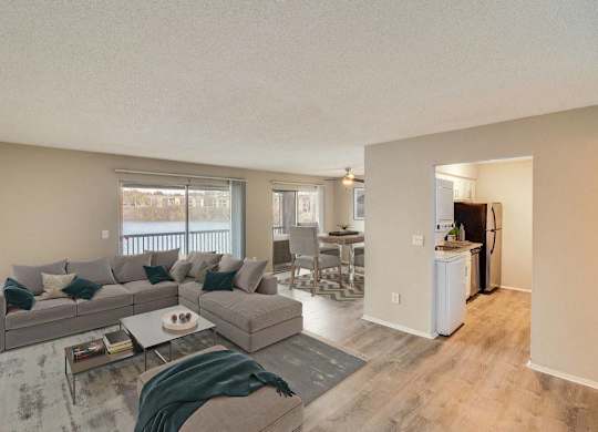 A living room with a grey couch and a coffee table at The Waverly on the Lake - Belleville, MI Apartment , Belleville, MI