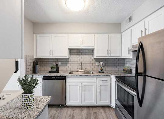 A kitchen with a black refrigerator and white cabinets at The Waverly on the Lake - Belleville, MI Apartment , Belleville, Michigan