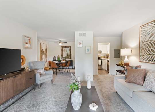 A living room with a grey couch and a wooden entertainment unit at The Waverly on the Lake - Belleville, MI Apartment , Michigan
