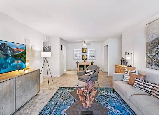 A living room with a couch, a chair, a coffee table, and a painting on the wall at The Waverly on the Lake - Belleville, MI Apartment , Michigan, 95050