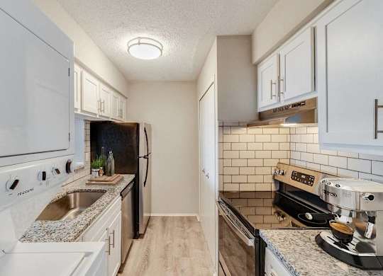 A kitchen with white cabinets and a black fridge at The Waverly on the Lake - Belleville, MI Apartment , Belleville, Michigan