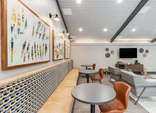 A room with a table, chairs and a wall of art at The Waverly on the Lake - Belleville, MI Apartment , Belleville, Michigan