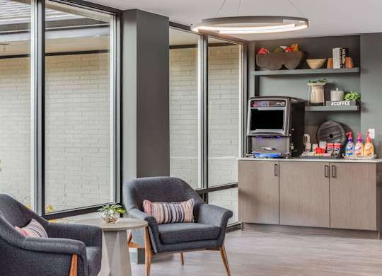 A modern living room with grey armchairs and a grey coffee table at The Waverly on the Lake - Belleville, MI Apartment , Michigan