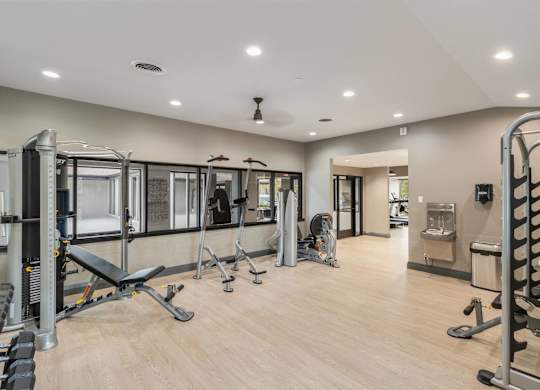A spacious gym with a variety of equipment including treadmills, weights, and exercise machines at The Waverly on the Lake - Belleville, MI Apartment , Belleville, MI