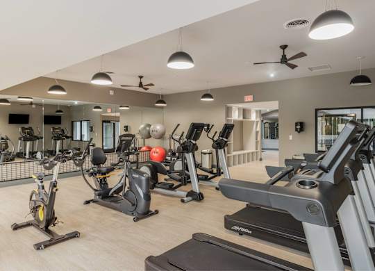 A gym with treadmills, elliptical machines, and other exercise equipment at The Waverly on the Lake - Belleville, MI Apartment , Michigan, 48111