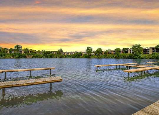 A serene lake with wooden benches and a sunset sky at The Waverly on the Lake - Belleville, MI Apartment , Michigan, 95050