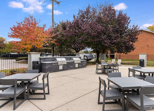 A park with tables and chairs surrounded by trees at The Waverly on the Lake - Belleville, MI Apartment , Michigan