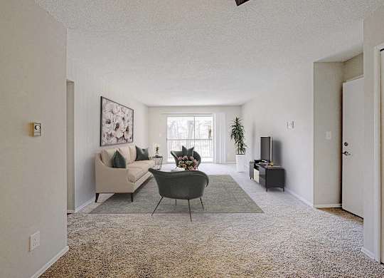 A living room with a couch, chair, and potted plant at The Waverly on the Lake - Belleville, MI Apartment , Belleville, MI