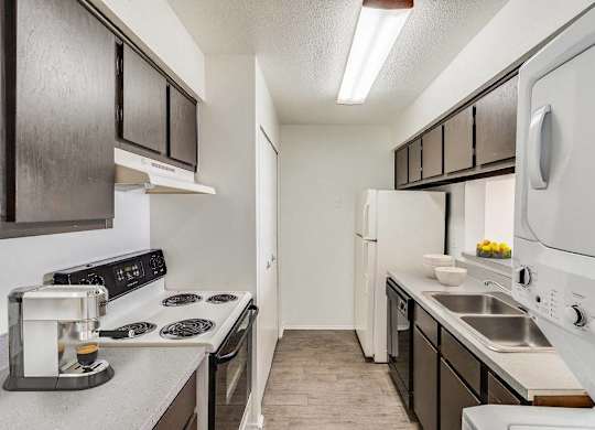 A kitchen with black cabinets and white appliances at The Waverly on the Lake - Belleville, MI Apartment , Belleville