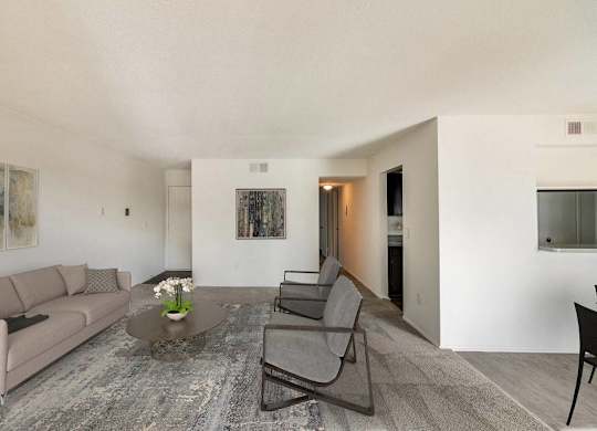 A living room with a grey couch, a coffee table, and a painting on the wall at The Waverly on the Lake - Belleville, MI Apartment , Belleville
