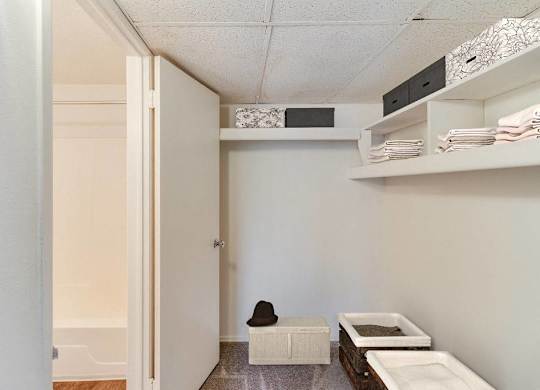 A small room with a white door and a white bench with a black hat on it at The Waverly on the Lake - Belleville, MI Apartment, Belleville, MI, 48111