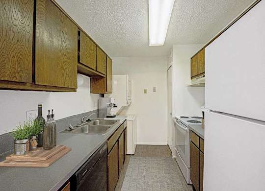 A kitchen with wooden cabinets and a white refrigerator at The Waverly on the Lake - Belleville, MI Apartment , Belleville, Michigan