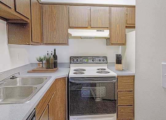 A modern kitchen with wooden cabinets and stainless steel appliances at The Waverly on the Lake - Belleville, MI Apartment, Belleville, MI, 95050