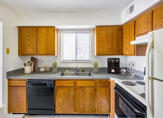 A kitchen with wooden cabinets and a black dishwasher at The Waverly on the Lake - Belleville, MI Apartment , Belleville