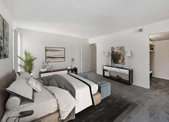 A bedroom with a bed, nightstand, and a plant at The Waverly on the Lake - Belleville, MI Apartment , Belleville, Michigan