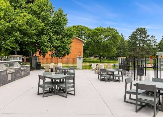 A park with tables and chairs and a fence at The Waverly on the Lake - Belleville, MI Apartment, Belleville, MI, 95050