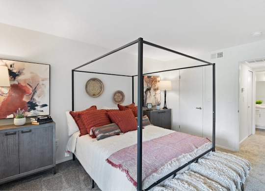 A bedroom with a four poster bed and a grey cabinet at The Waverly on the Lake - Belleville, MI Apartment , Belleville, Michigan