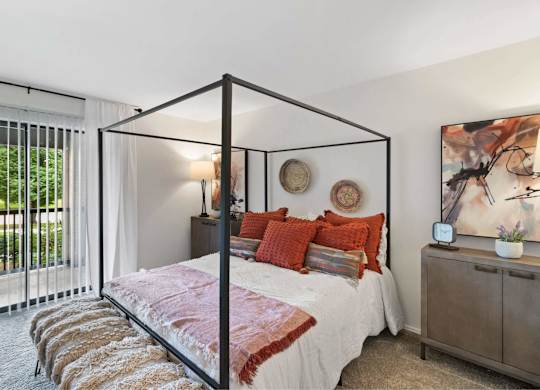 A bedroom with a four poster bed and a painting on the wall at The Waverly on the Lake - Belleville, MI Apartment , Michigan