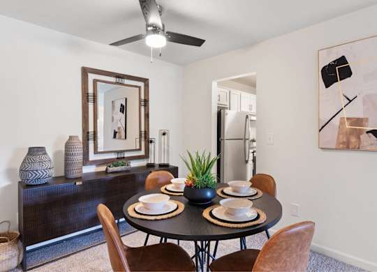 A dining room with a table set for two and a ceiling fan at The Waverly on the Lake - Belleville, MI Apartment , Belleville, MI
