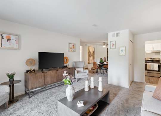 A modern living room with a grey carpet and a wooden entertainment center at The Waverly on the Lake - Belleville, MI Apartment , Michigan, 95050