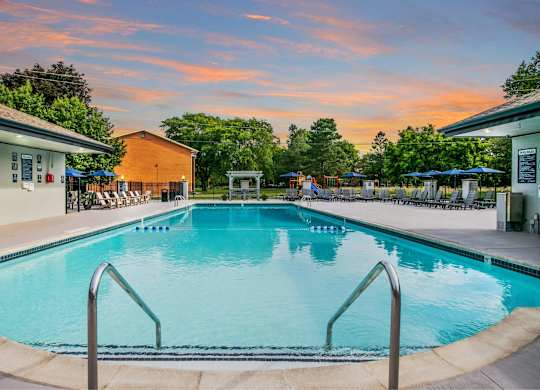A large swimming pool with a metal ladder in the foreground at The Waverly on the Lake - Belleville, MI Apartment , Belleville, MI
