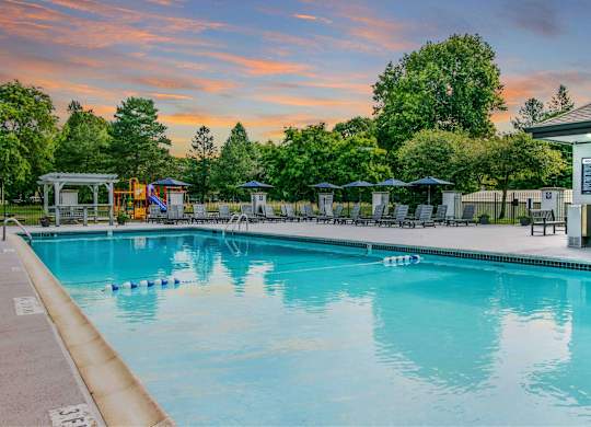 A large swimming pool with a sunset in the background at The Waverly on the Lake - Belleville, MI Apartment , Belleville, Michigan