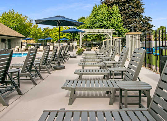 A poolside area with sun loungers and umbrellas at The Waverly on the Lake - Belleville, MI Apartment , Michigan