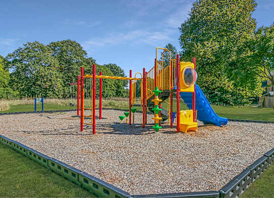 A playground with a yellow slide and a green slide at The Waverly on the Lake - Belleville, MI Apartment , Michigan, 95050