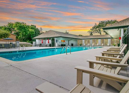A poolside area with sun loungers and a building in the background at The Waverly on the Lake - Belleville, MI Apartment , Michigan