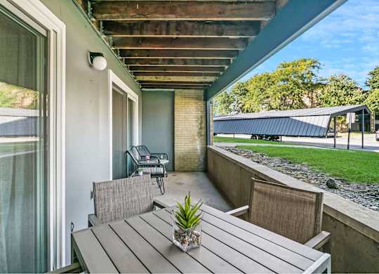 A wooden table with a potted plant on it sits on a patio at The Waverly on the Lake - Belleville, MI Apartment , Belleville, Michigan