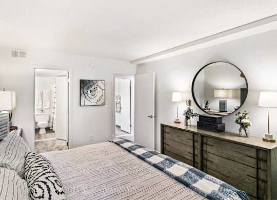 A bedroom with a bed, dresser, and mirror at The Waverly on the Lake - Belleville, MI Apartment , Belleville, MI