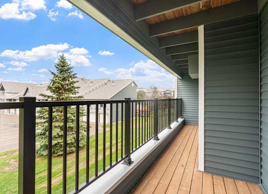 A balcony with a black railing and a wooden floor.